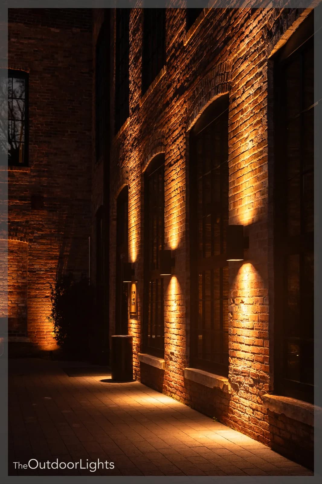 Warm uplighting tracing the arched brick facade of a building at night