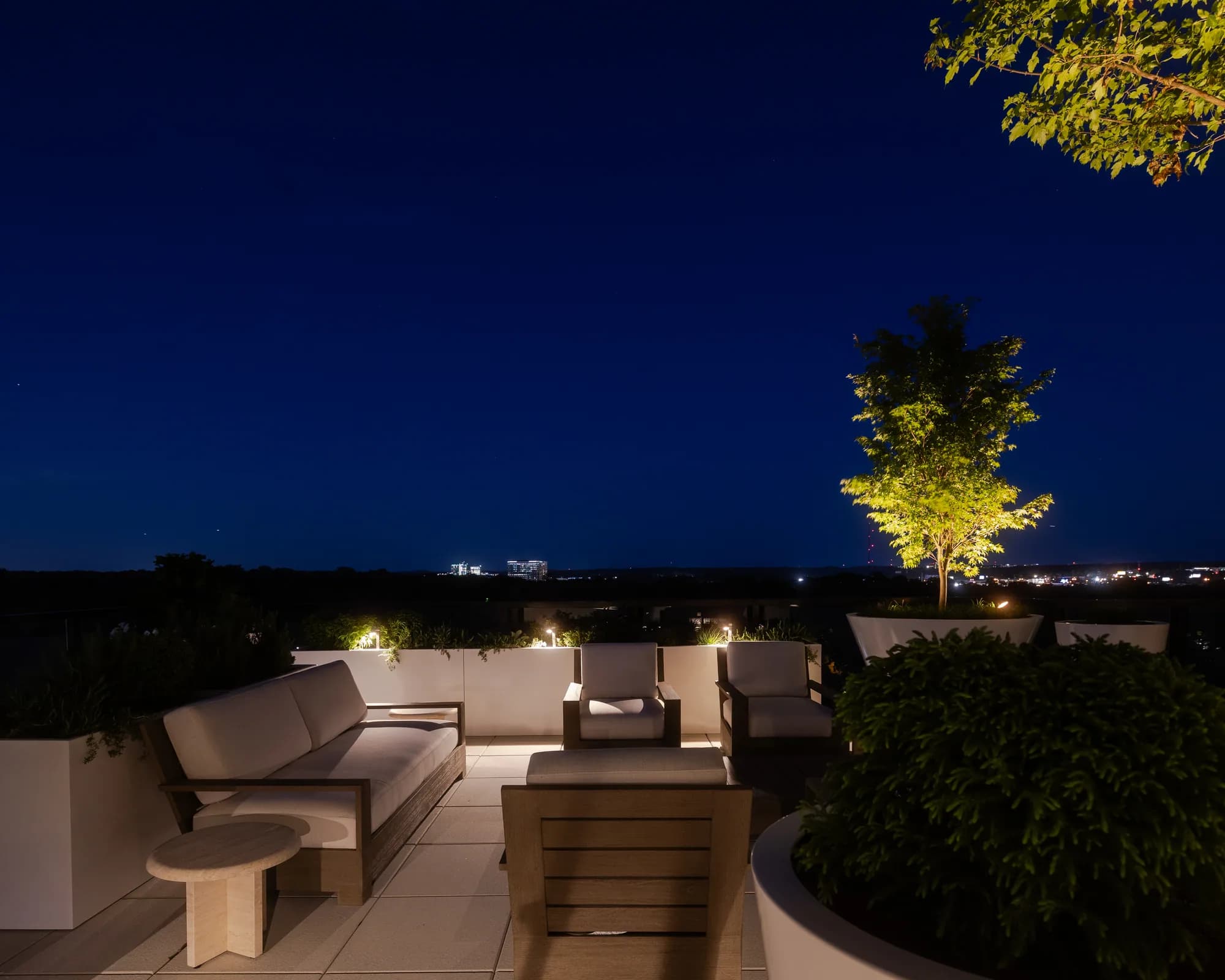 Craft Terrace rooftop seating with illuminated planters and trees at night