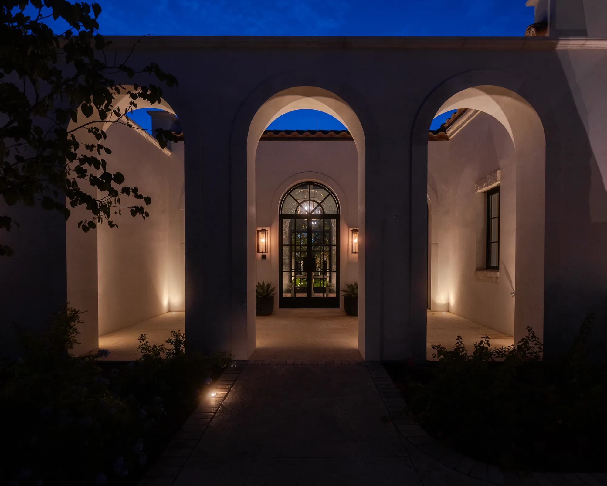 Warm uplights illuminating the arched entrance of the Forrest Jr. estate in Texas