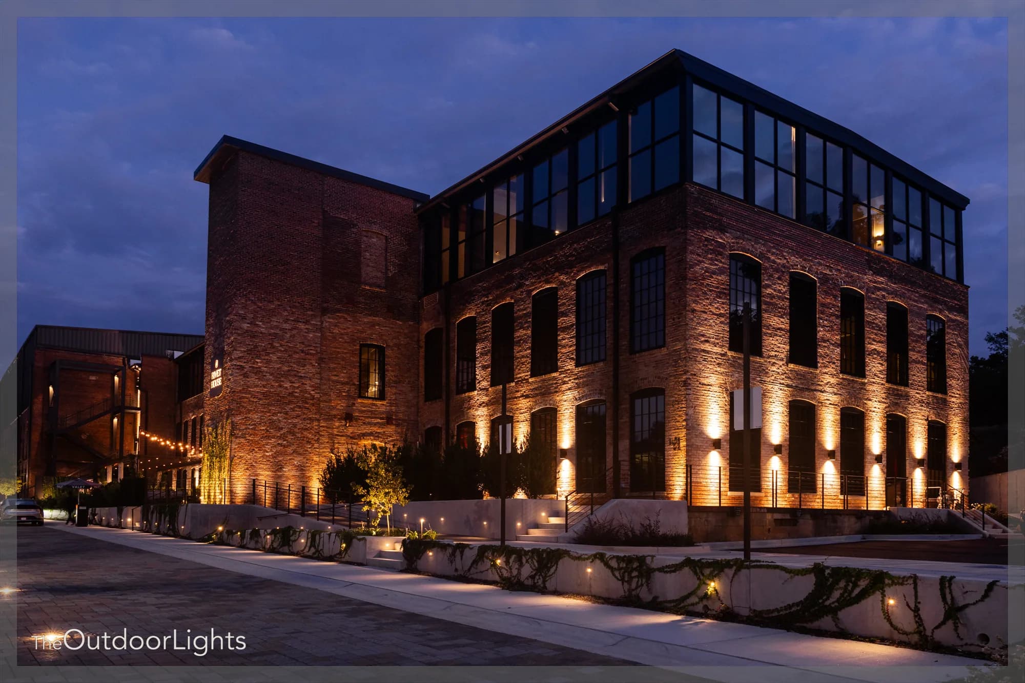 Athens Rivet House Hotel with warm uplighting across its brick facade at dusk