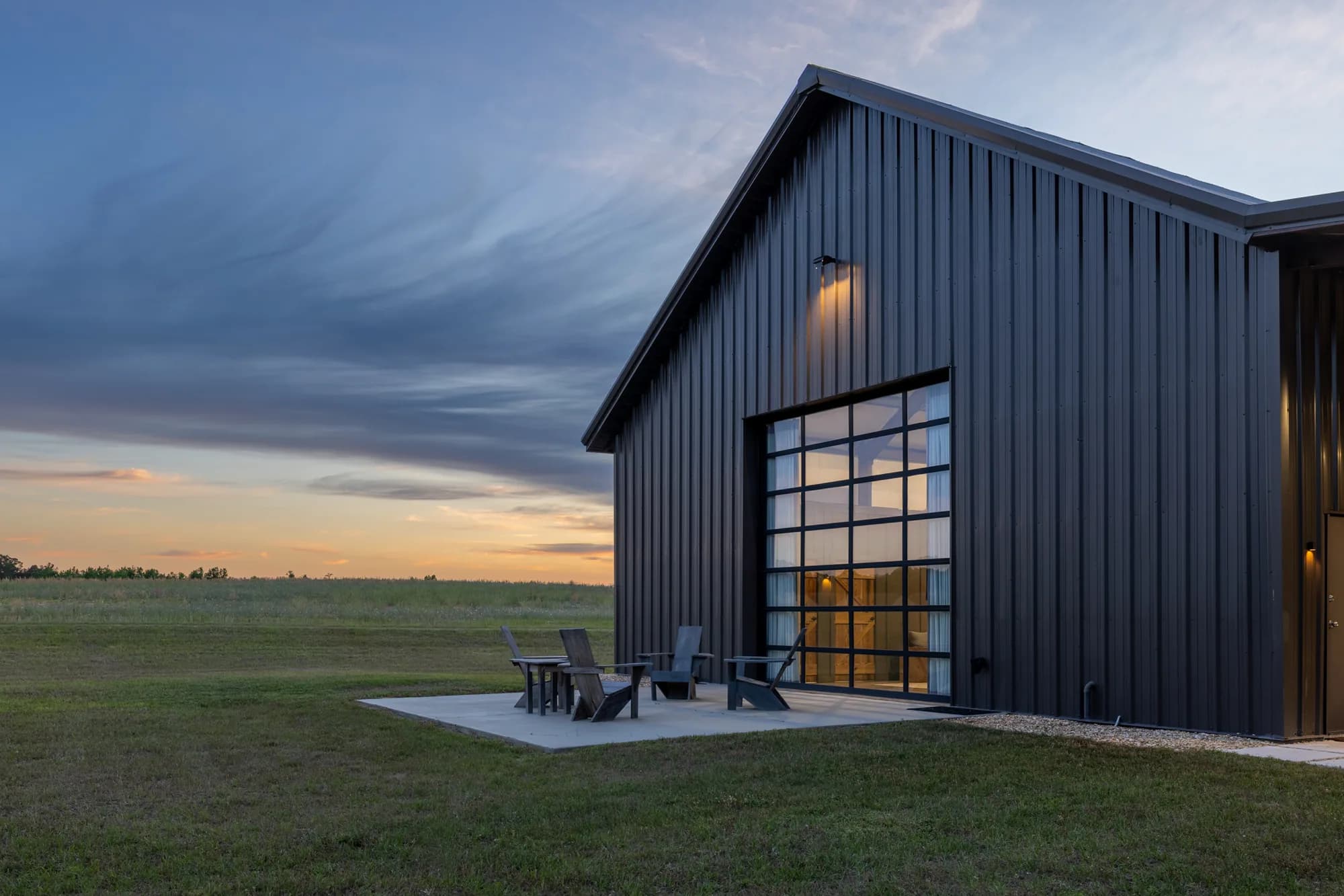 Wake Farm barn with warm lighting above its tall glazed entrance at dusk